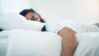Man asleep in bed, lying on his stomach