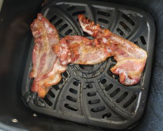 Three rashers of cooked streaky bacon in the Gourmia 4-quart digital air fryer basket
