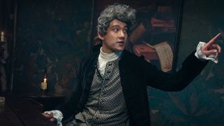 Will Sharpe sits at a piano while point a finger the other way