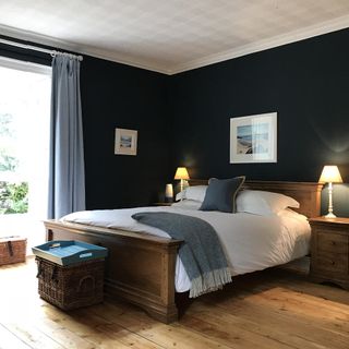 bedroom with navy wall wooden floor and bed