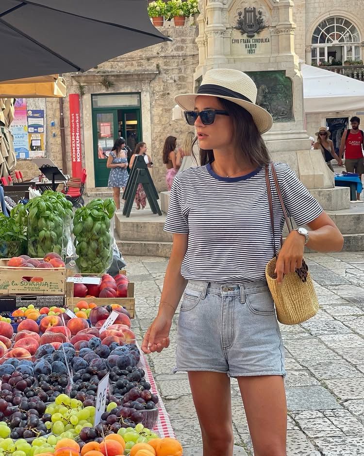 @leasy_inparis wears a pair of short denim shorts with a stripe top and straw hat