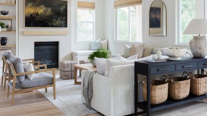 living room with white sofa and black console table with grey armchairs and painting over fireplace