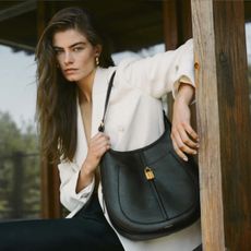 Woman wears cream blazer, black trousers and black leather bag