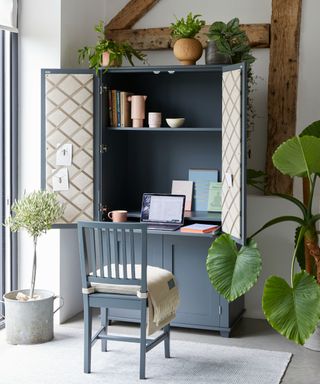 Freestanding home office unit in dark painted finish, with padded notice board panels on cabinet doors, and pull-out desk.