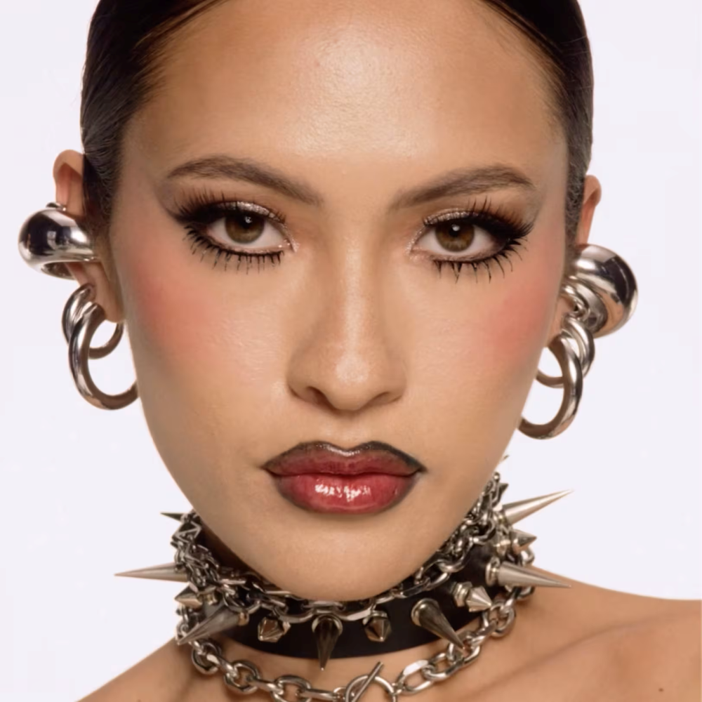 Model wearing Halloween inspired make up sold at MAC with spike collars and layered earring stack