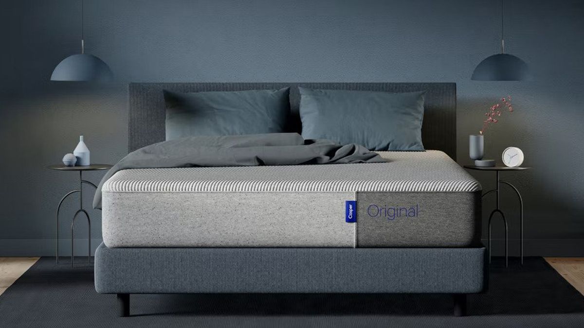 The Casper Original Mattress placed on a grey fabric bed frame in a dusky blue bedroom