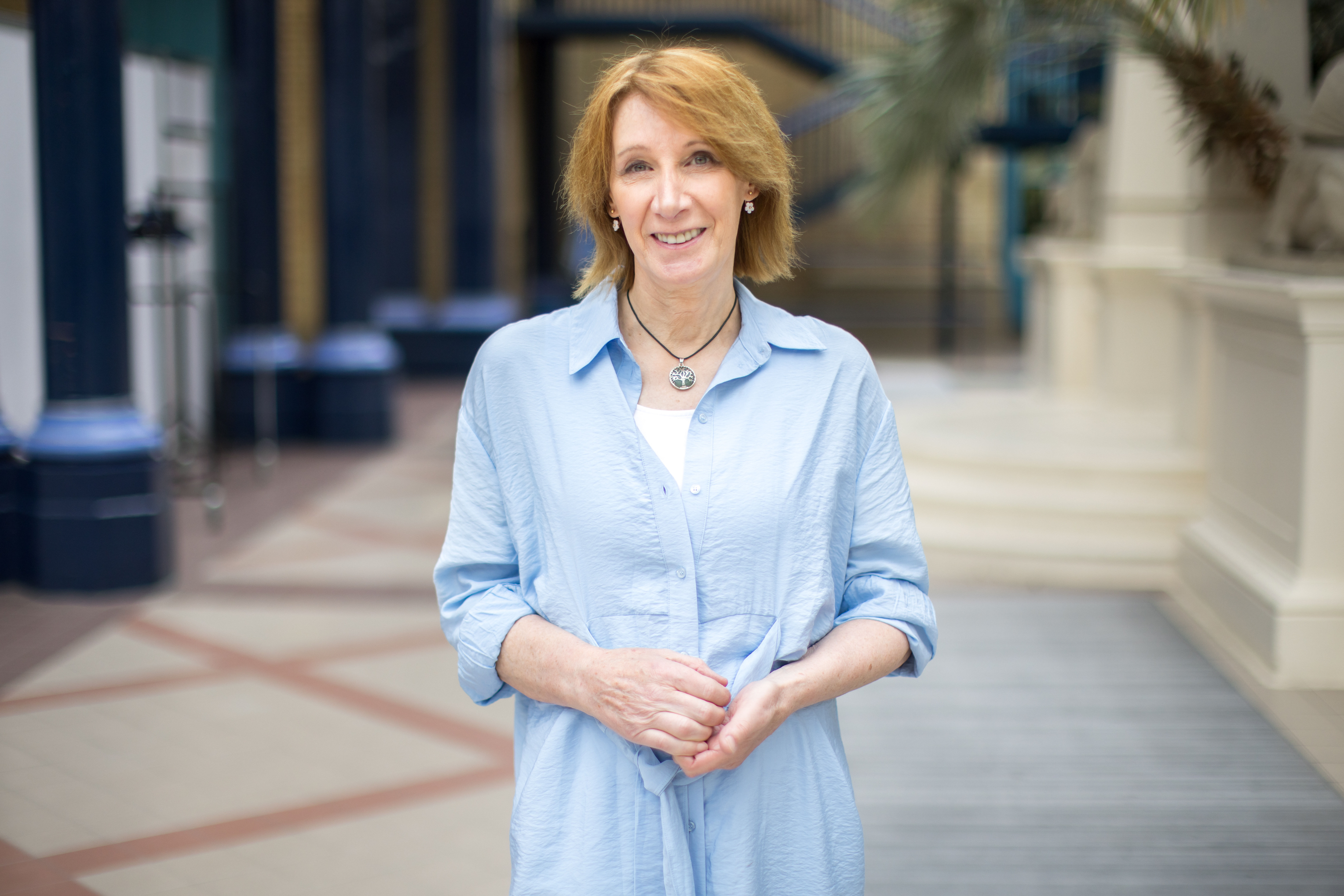Retired cyclist Philippa York stands in front of a soft background wearing a blue shirt