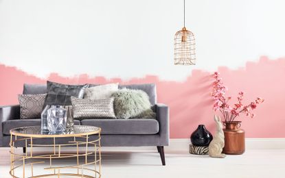 A grey sofa with assorted scatter cushions against a pink and white wall