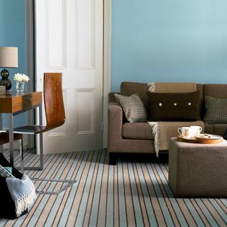 blue living room with striped carpet and brown sofa
