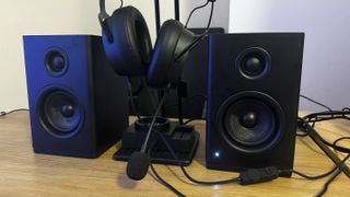 The NZXT Relay speakers, headphones and stand on a wooden table