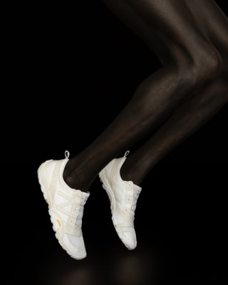 Picture of legs jumping on a black background wearing Issey Miyake x New Balance sneakers