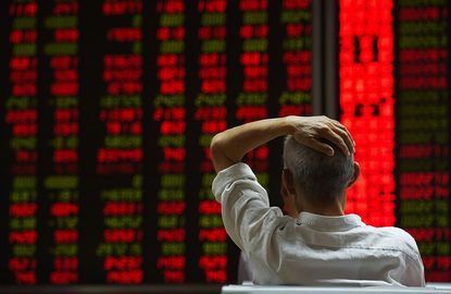 An investor looks at screens showing stock market movements at a securities company in Beijing on July 14, 2015.