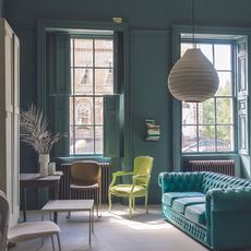 living room with teal green walls and button back sofa