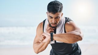 Man looking at GPS sports watch while checking pulse