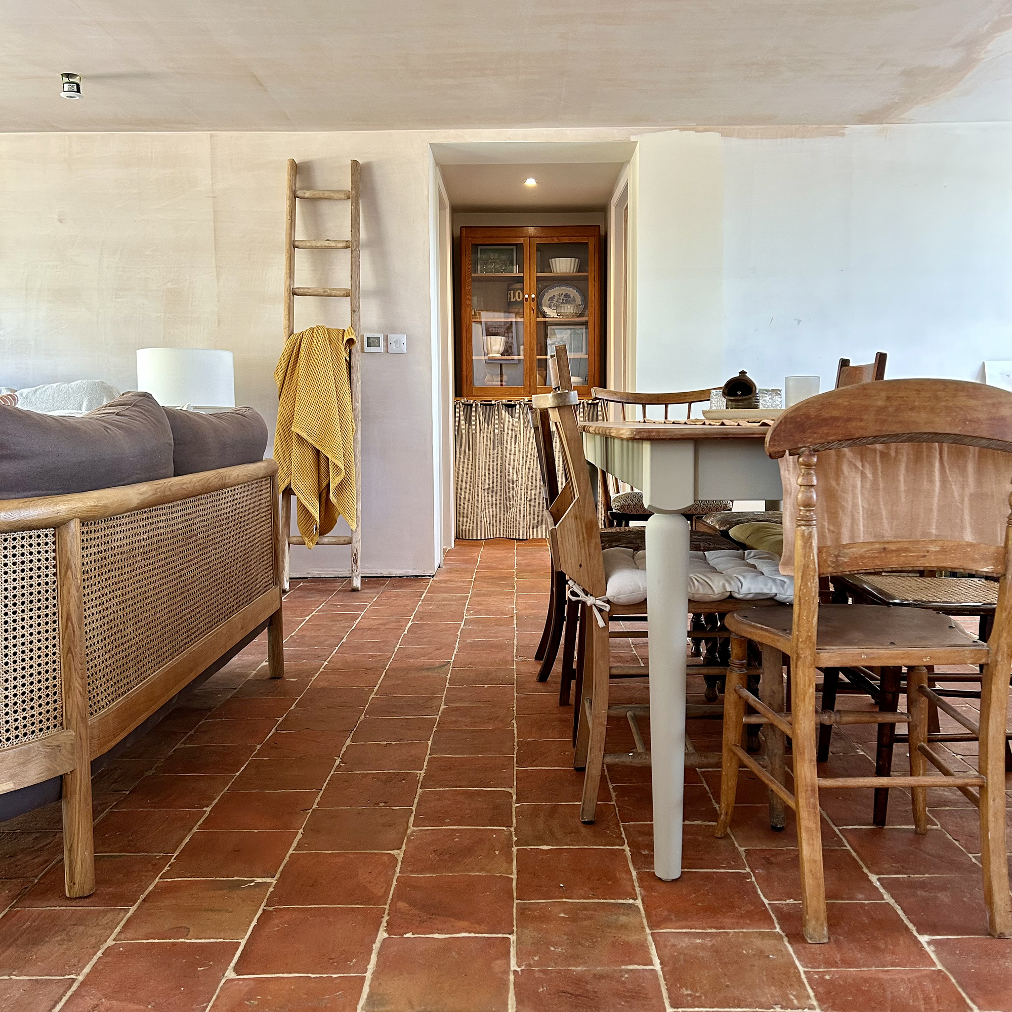 neutral living room with rustic dining table and terracotta floor tiles