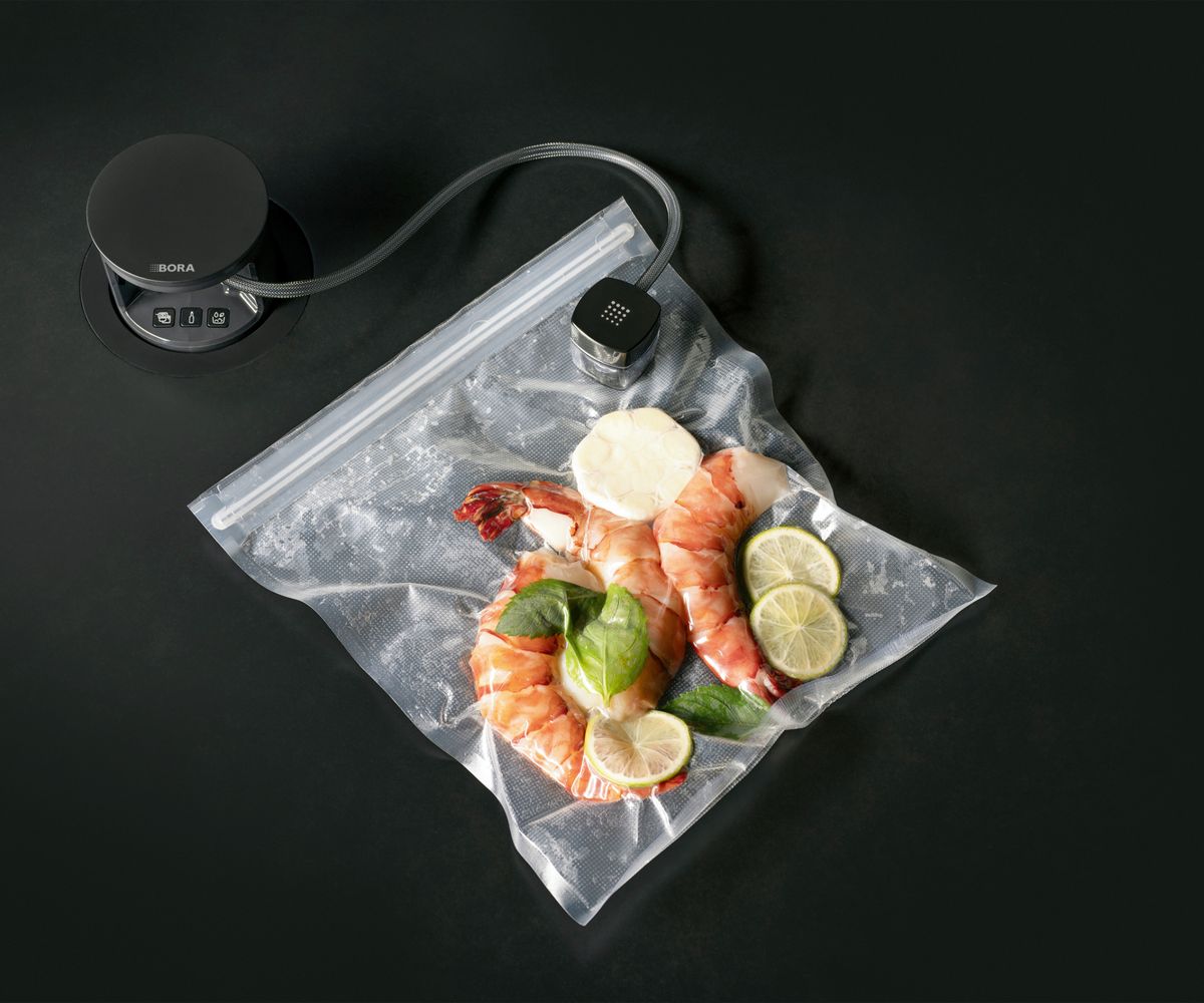 Bora QVac inset into kitchen island showing it in use on bottle and pack of food