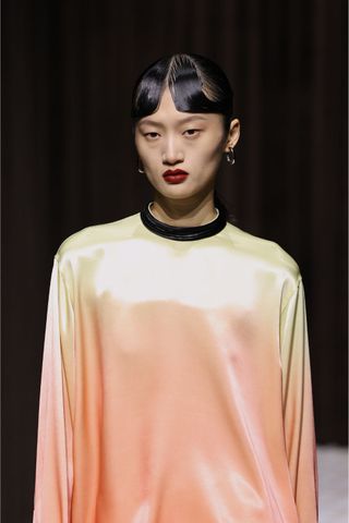 Model at Jil Sander wearing crimson lips, a key Spring/Summer 2025 fashion month beauty look