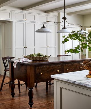 Vintage wooden kitchen island with pendant light above and basket of artichokes in centre
