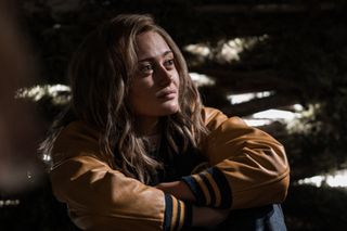 Ella Purnell as Teen Jackie wearing a lettman jacket and crossing her arms in YELLOWJACKETS.