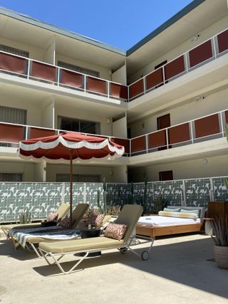 The pool area at Life House Palm Springs with umbrellas and lounge chairs.