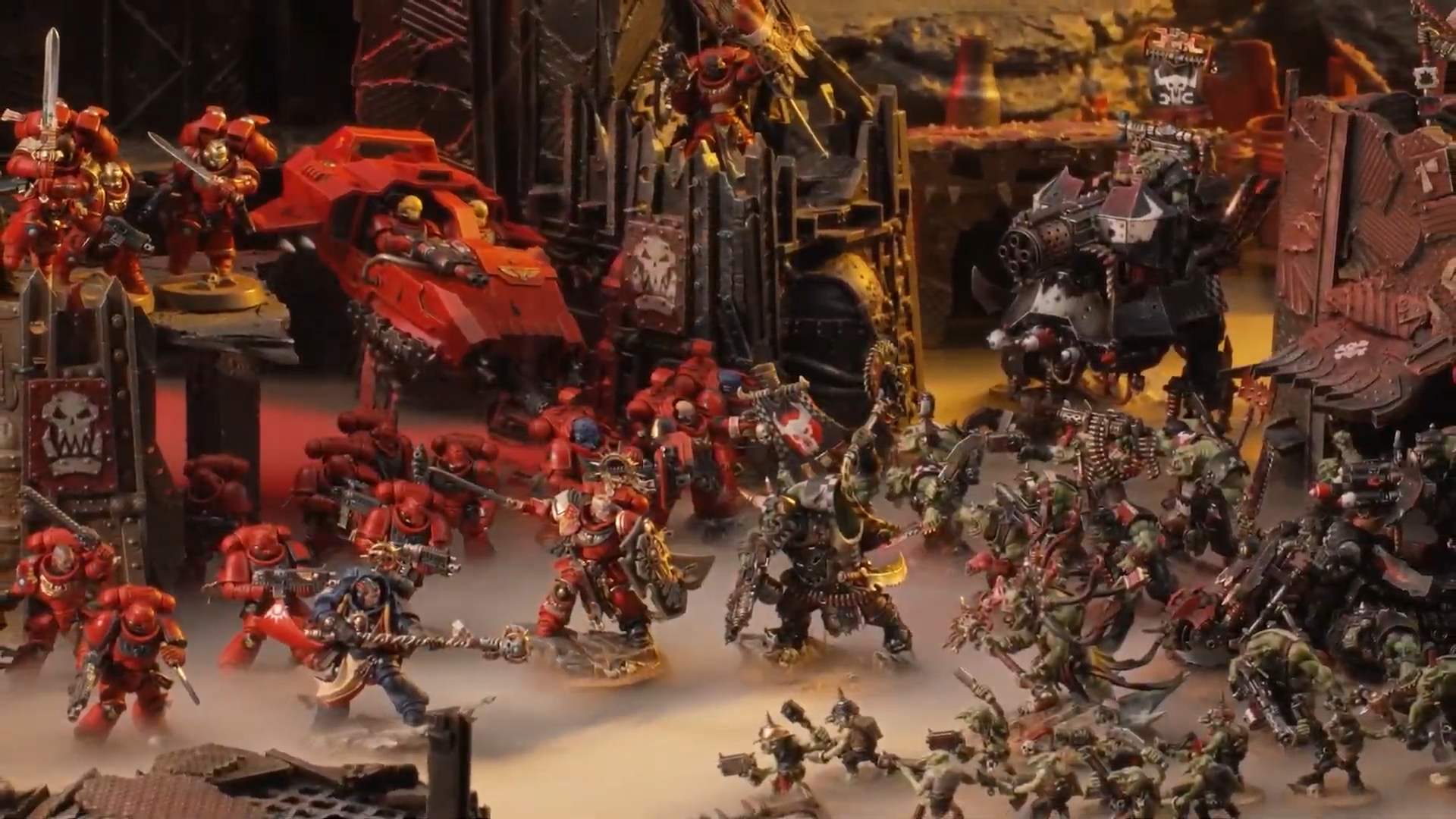A host of Space Marine and Ork models face off on a Warhammer 40K battlefield