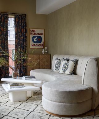 living room with lime wash walls, cream curved sofa and cream rug, white sculptural coffee table