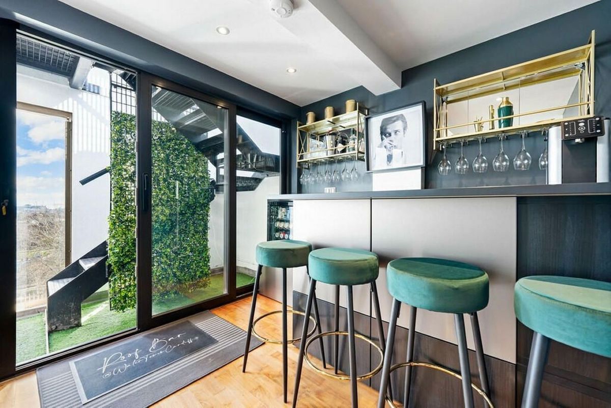 newly installed indoor bar next to glass wall with three bar stools in clean design