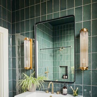 A green tiled bathroom with a matching ceiling and wall lights on either side of the mirror