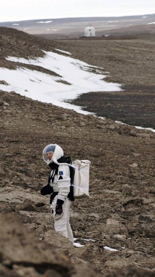 A Mars 160 crew member searches a hillside on an EVA.