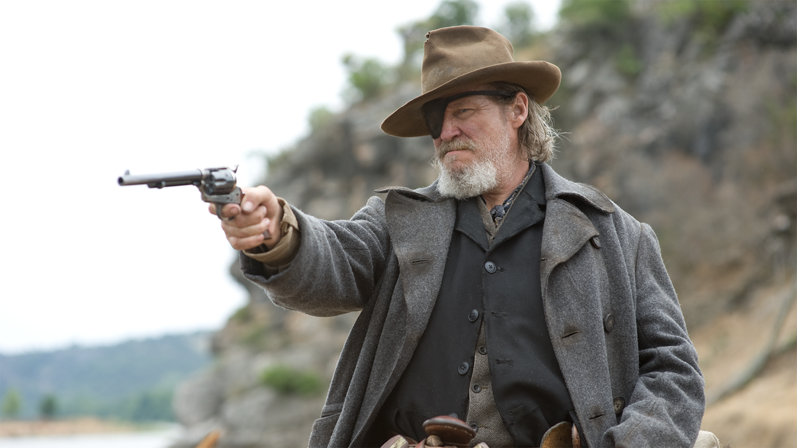 A still from the movie True Grit in which Jeff Bridges' character Deputy U.S. Marshal Rooster Cogburn points a gun off-camera.
