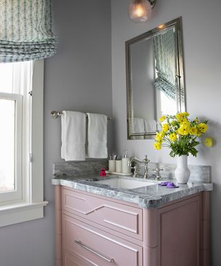 bathroom with gray walls and pink washstand with marble countertop