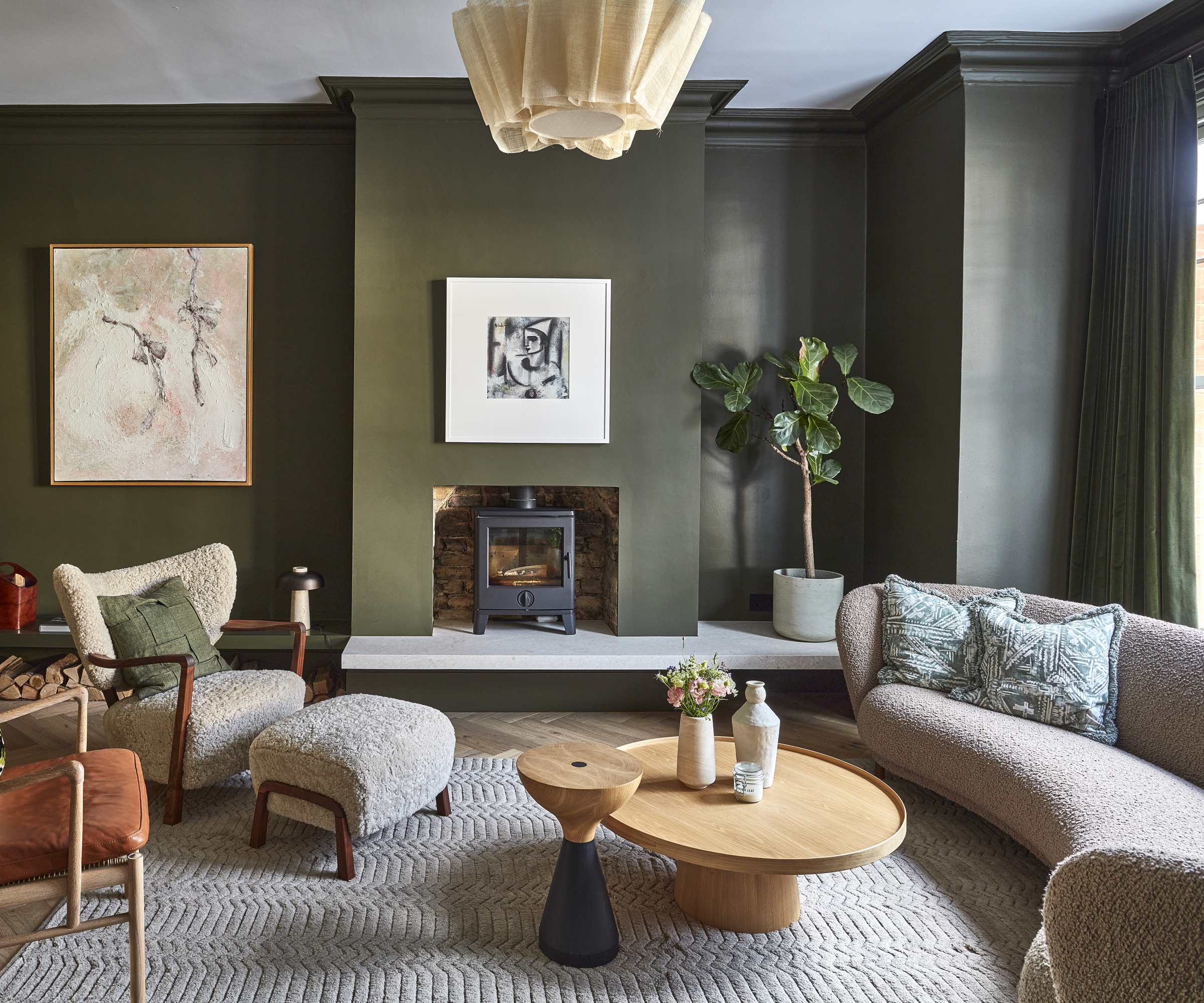 living room with green walls, curved sofa, occasional chairs, coffee tables and log burner inset into wall