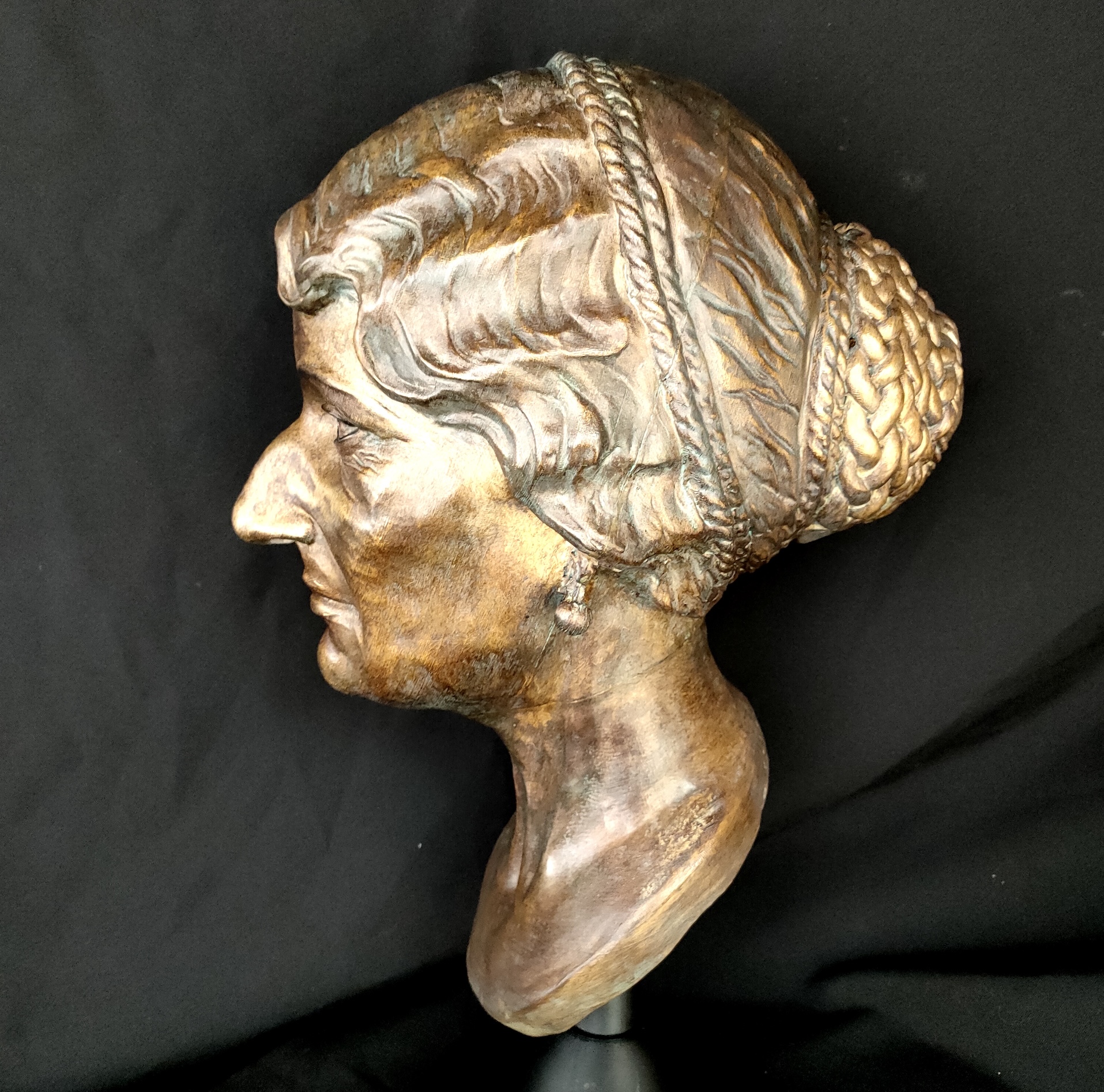 Side view of a bronze sculpture of a female mummy.
