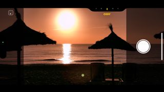 The Apple iPhone 16 camera screen showing a sunset over the ocean with parasols in the foreground