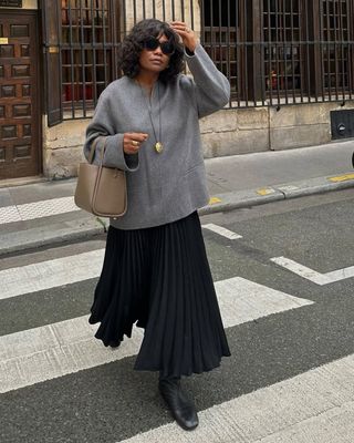 Franny in a pleated skirt and grey top