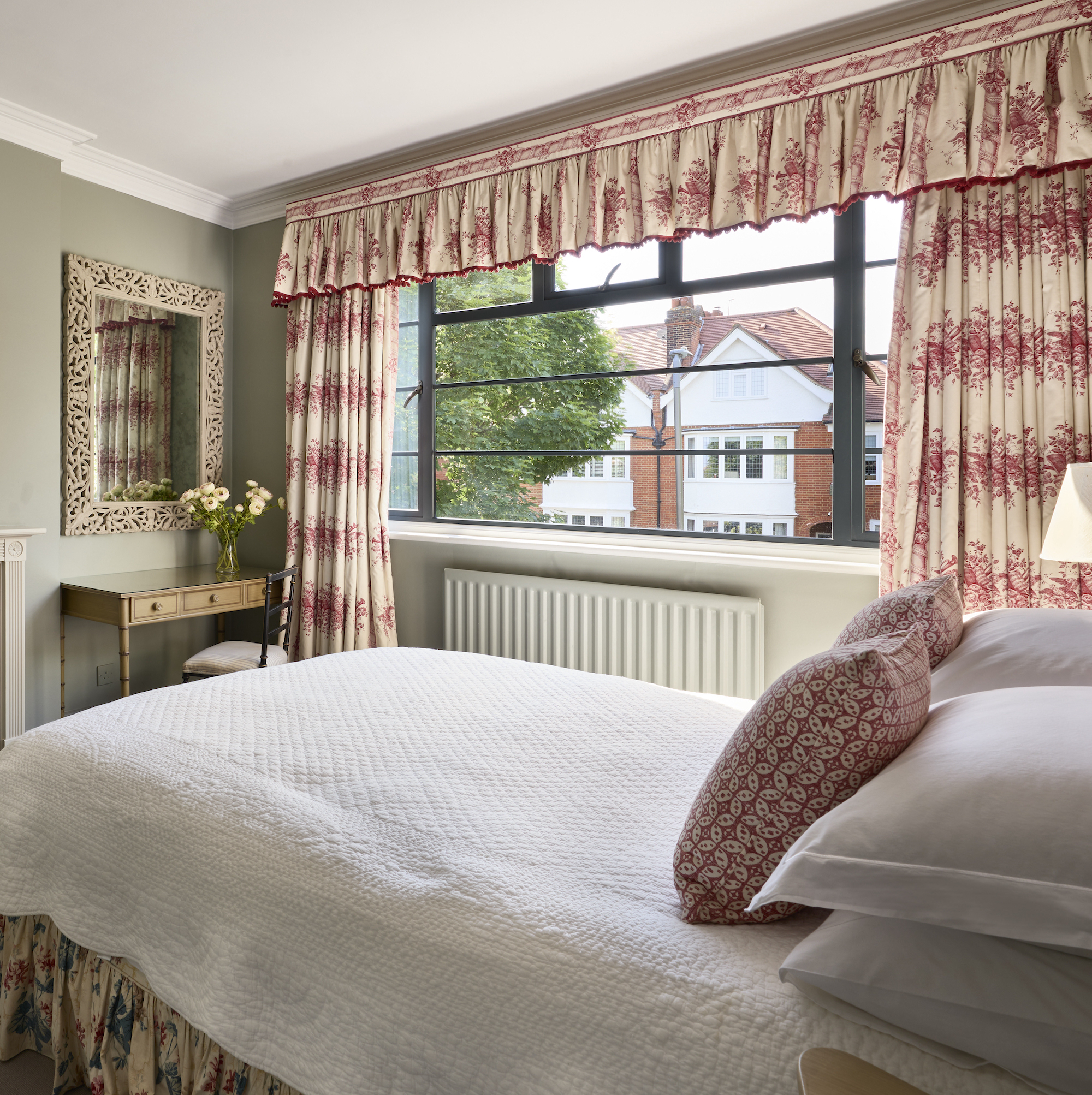 bedroom with green painted walls and red and white curtains with pelment