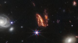 This twisty, orange N-shaped galaxy is seemingly being ripped apart by a galactic merger.