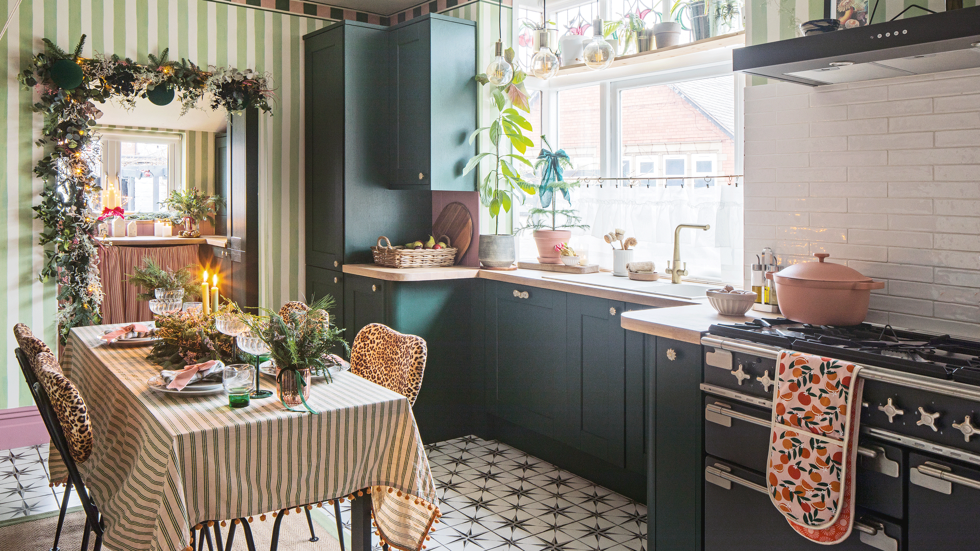 a kitchen diner with green cabinetry, green and white striped wallpaper, a dining table with a matching tablecloth and dining chairs upholstered in leopard print fabric