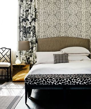 Luxury bedroom ideas illustrated with patterned wallpaper and soft furnishings in a black and gold scheme.