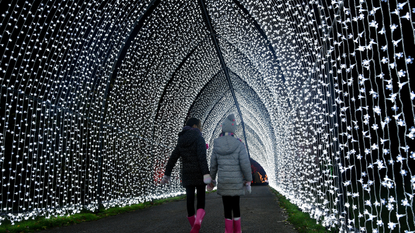 Two young children walking through illuminated festive display