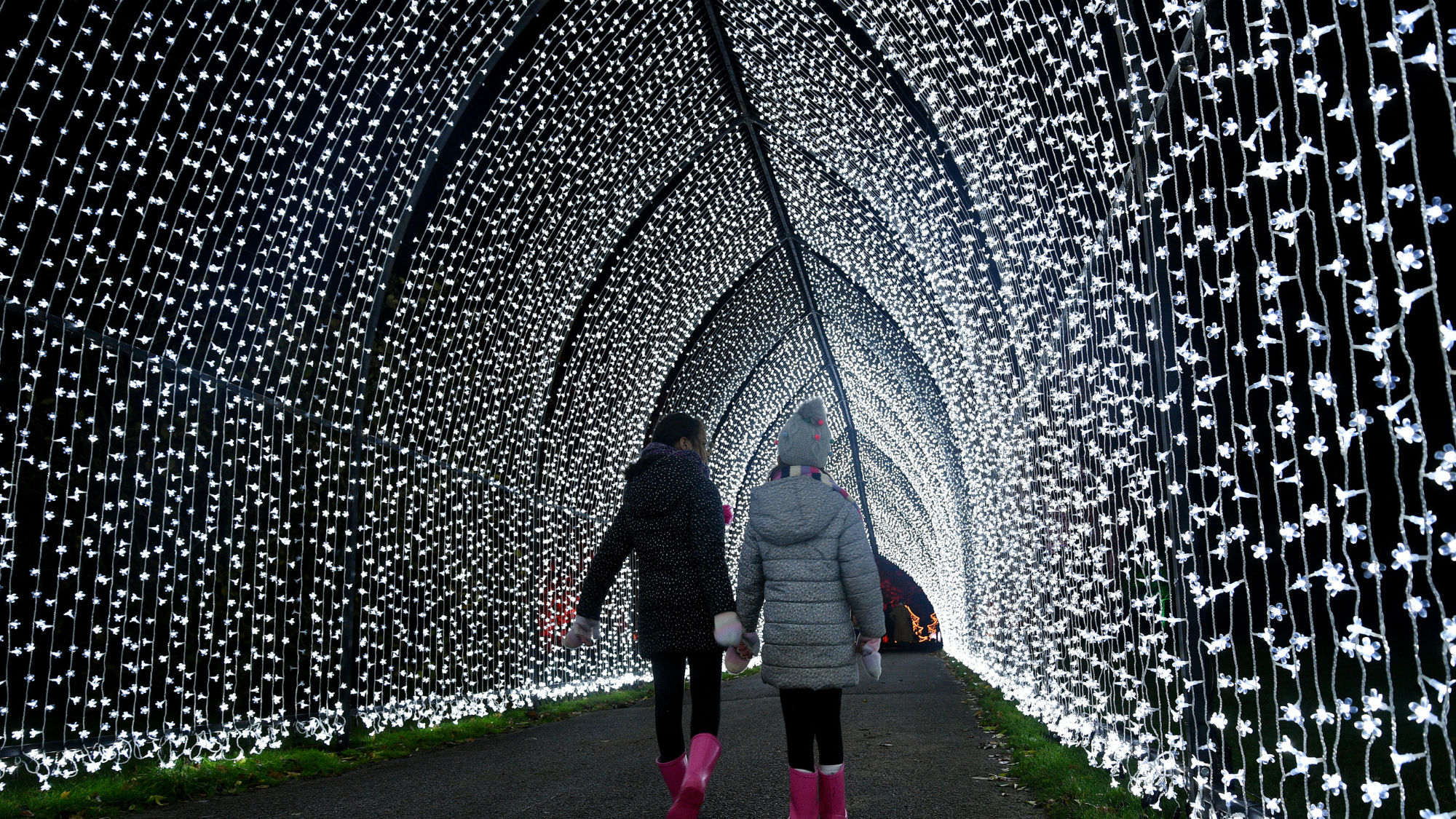 Two young children walking through illuminated festive display