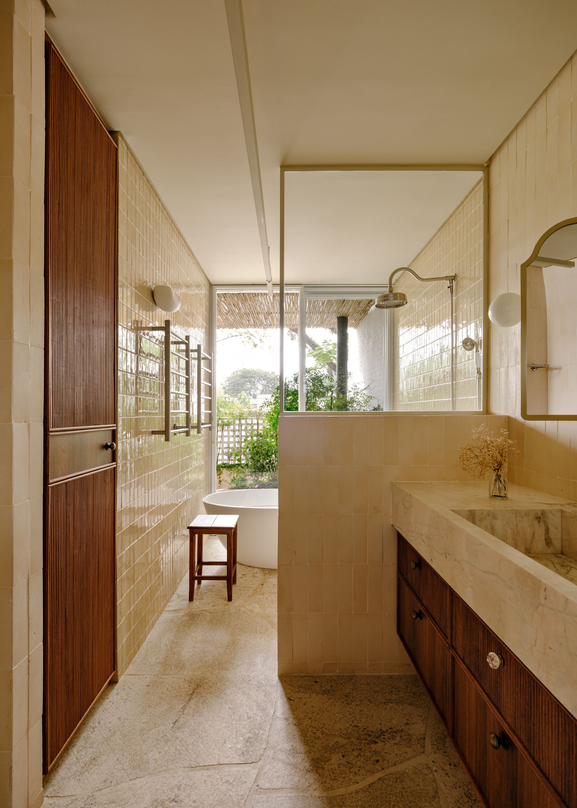 A bathroom in muted tones, with walls in zellige tiles and floor in stone