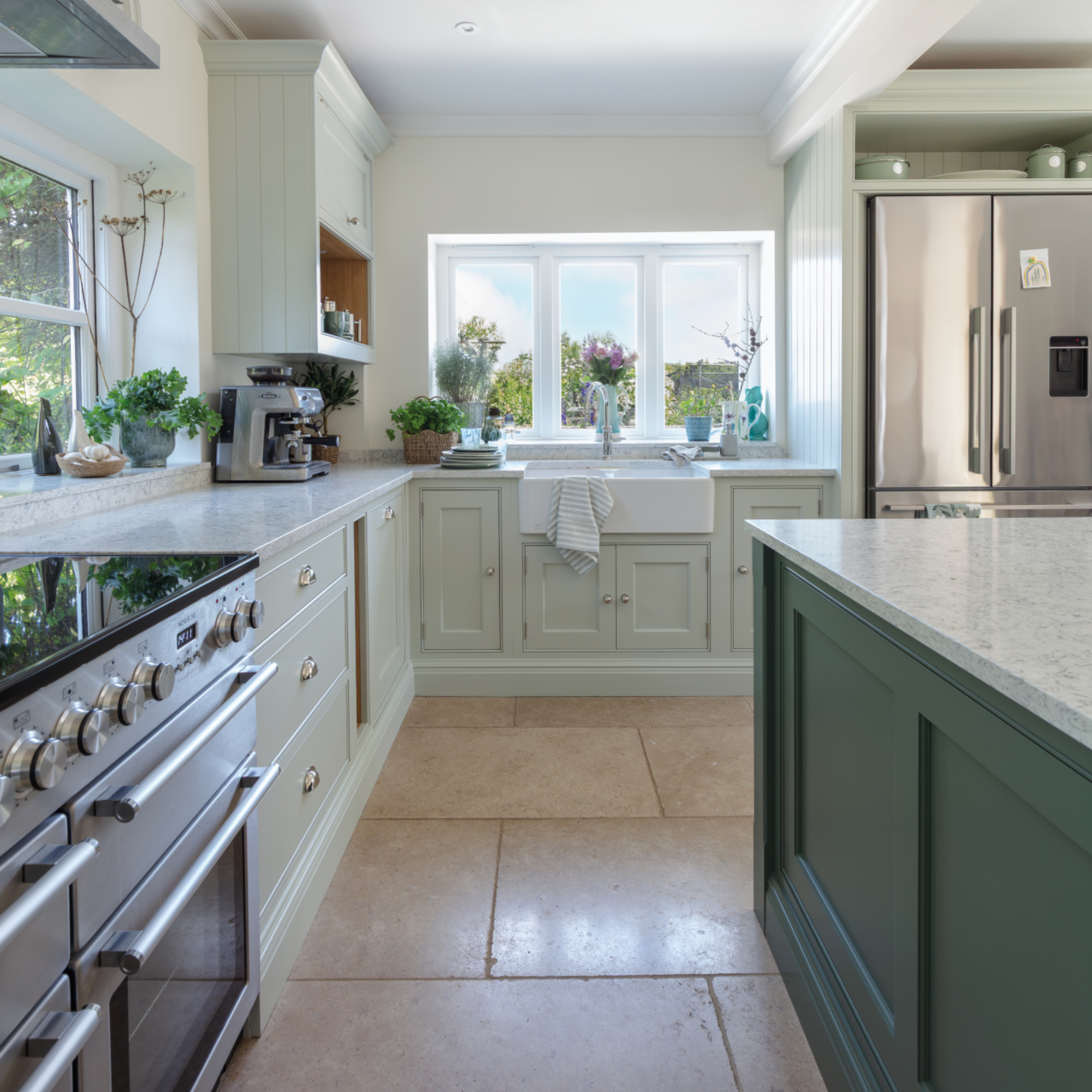 two tone green kitchen with darker green island, marble worktops, stone floor, range cooker, American style fridge