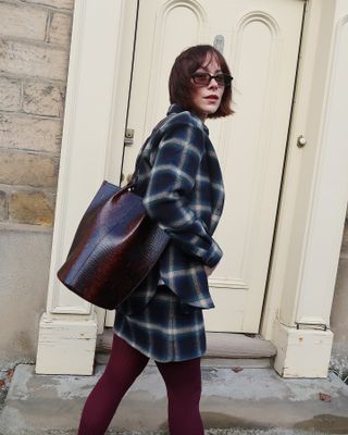 Fashion influencer @meganellaby wearing a chic winter outfit styled with 2024/2025's burgundy tights trend.