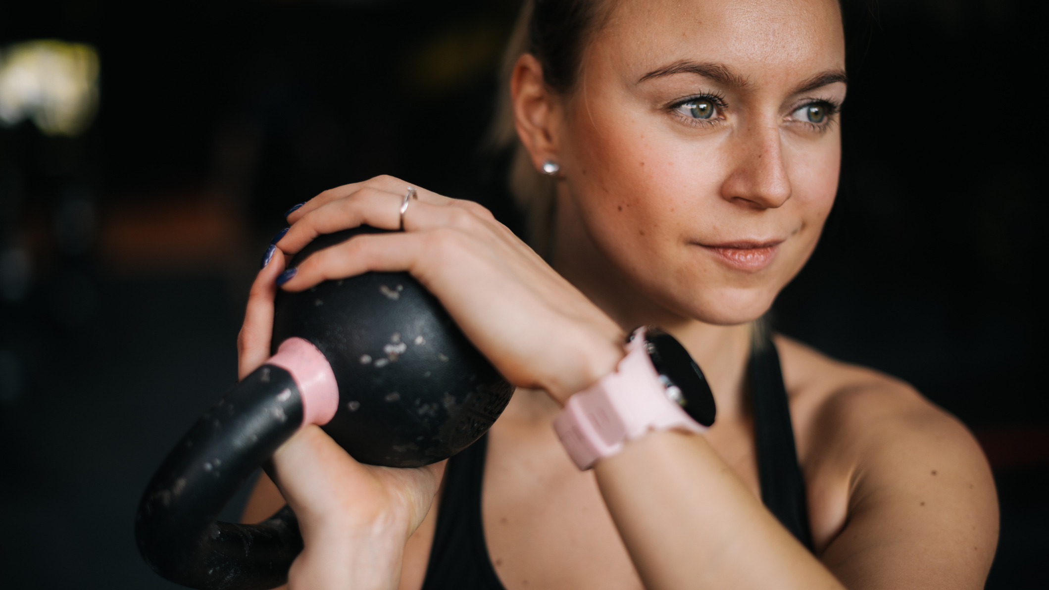 A woman holds a kettlebell next to her head