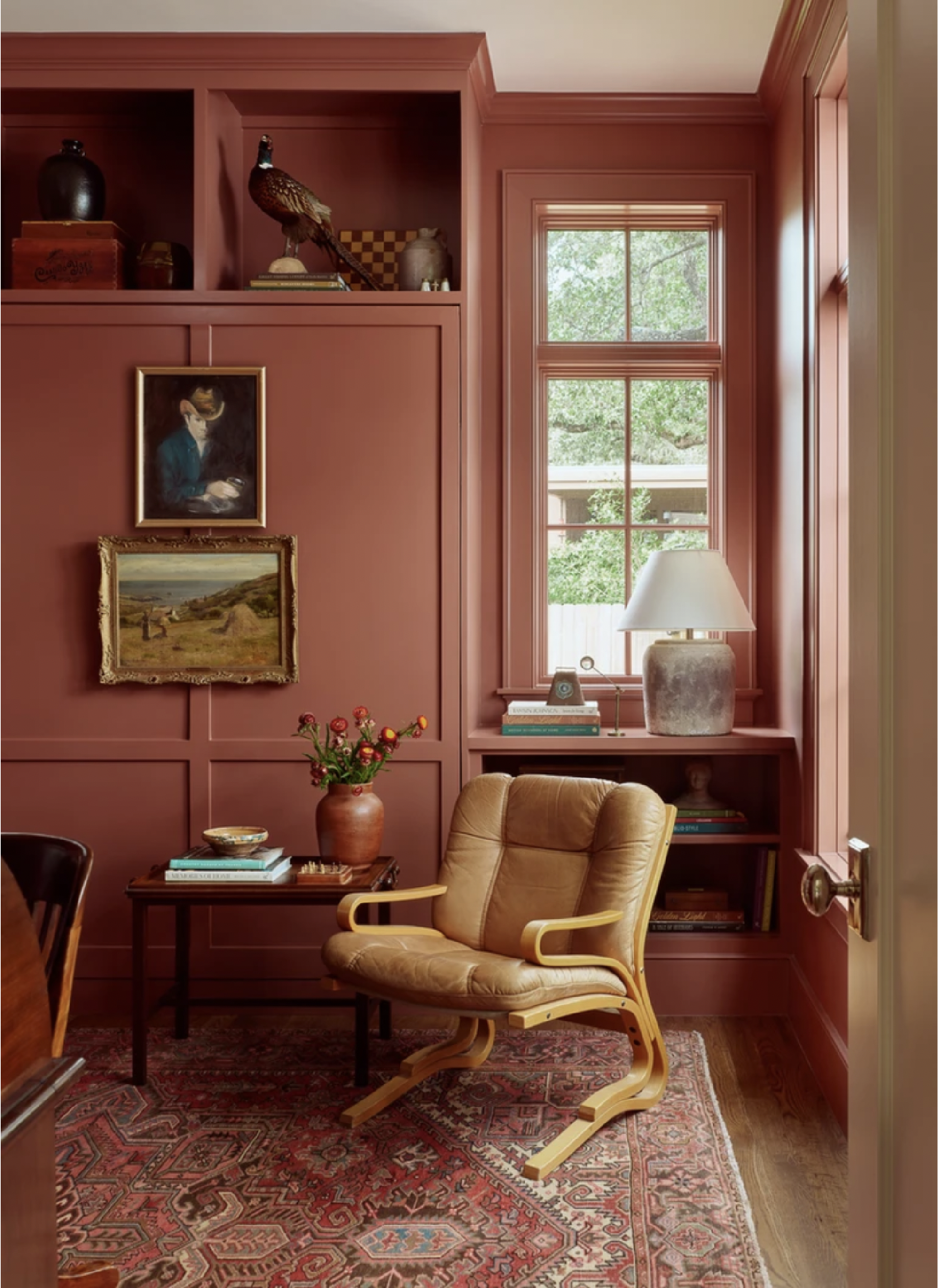 A living space with pink walls, molding, a pink pattered rug, and a leather accent chair