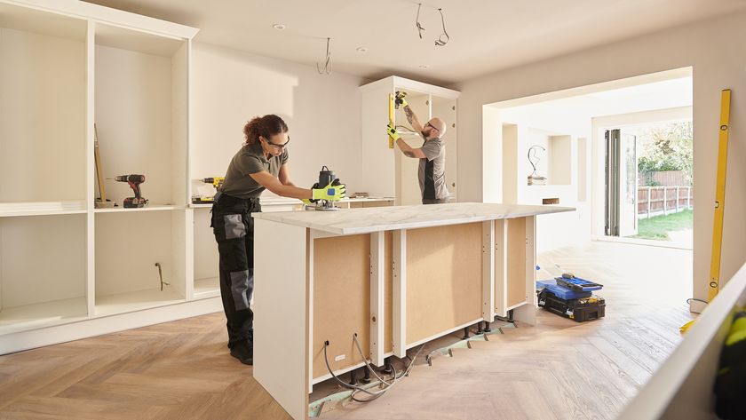 Two people fitting kitchen with island and wall cabinets