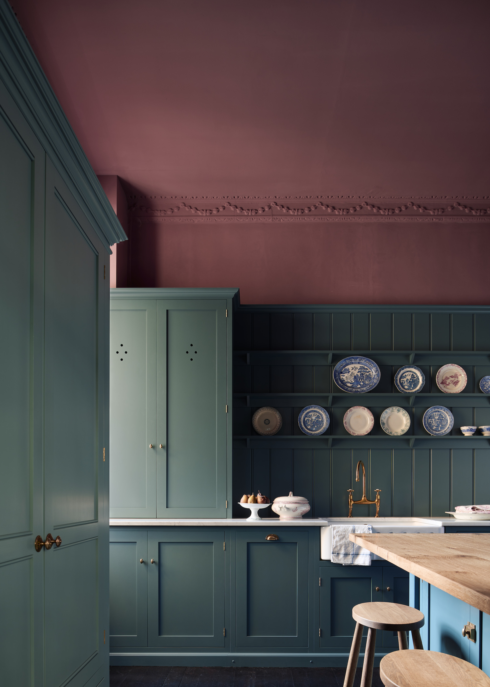 a dark teal kitchen in a traditional style with a burgundy painted wall and roof overhead