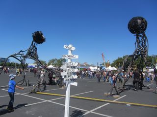 A sign points the way to rockets and more while strange sculptures stand guard at Maker Faire Bay Area 2013.