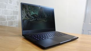 Image shows an open Razer Blade 14 laptop on a wooden table, turned off.
